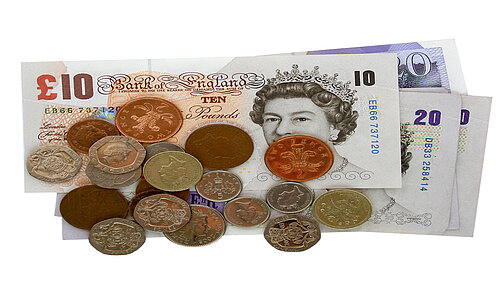 A pile of pound coins on top of notes.